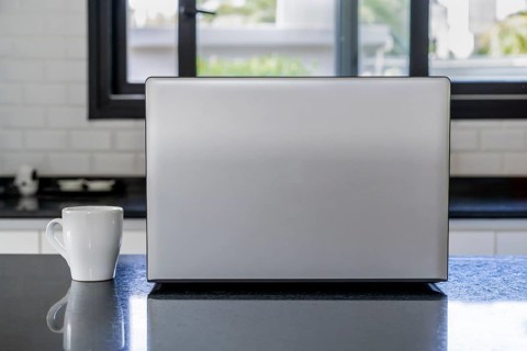 Laptop and cup of coffee on the kitchen island. Home office concept