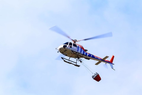 Helicopter with a water bucket during a forest fire, Tyrol, Austria, Europe