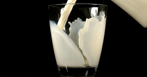 Milk being poured into Glass against black Background