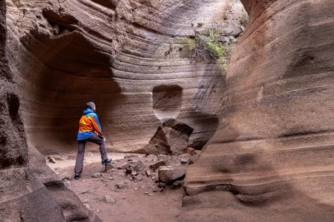 Tourist in sportswear visiting Slot Canyon Toba de Colores, Barranco de las Vacas, Agüimes, Las