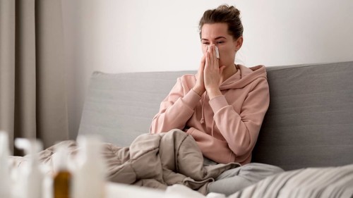 Woman indoors blowing her nose