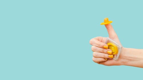 Woman holding yellow condom her finger