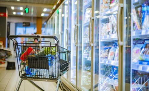 A shopping cart with grocery products in a supermarket