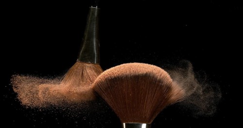 Make-up Brush spreading blush powder on black background