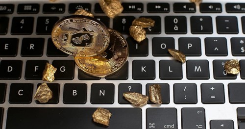 Bitcoins and Gold Nuggets on Computer Keyboard Background