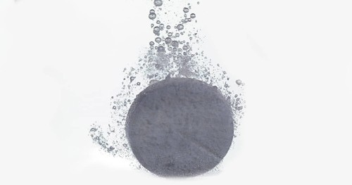 Tablets Falling and Dissolving into a Glass of Water against White Background