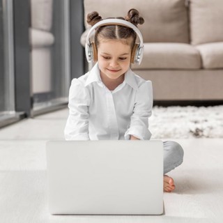 Little girl listening her teacher through headphones home
