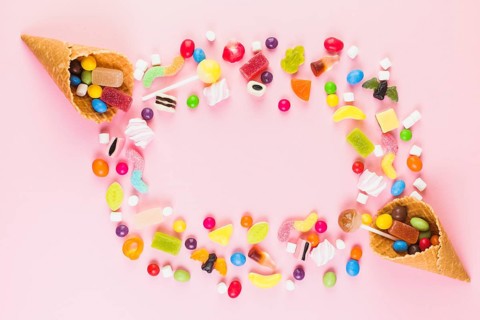 Colorful sweet candies with two ice cream waffle cone pink surface