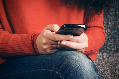 close-up of female hands using smart phone typing text message. with faded color retro filter