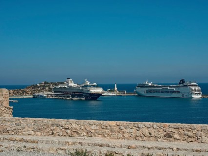 Cruise ships in the harbour with stone wall in the foreground under a clear blue sky, ibiza,