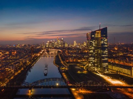 The lights of the European Central Bank (ECB) and the Frankfurt banking skyline glow in the evening
