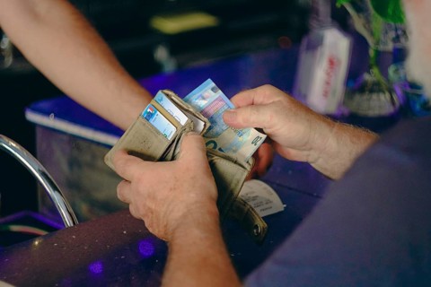 Parma, Italy July 24th 2024 A customer pays the barman at a cafe with a ten euro banknote.