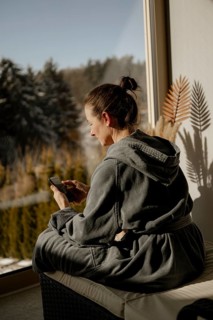 Woman in bathrobe sitting with mobile phone in a relaxation room during a wellness meal