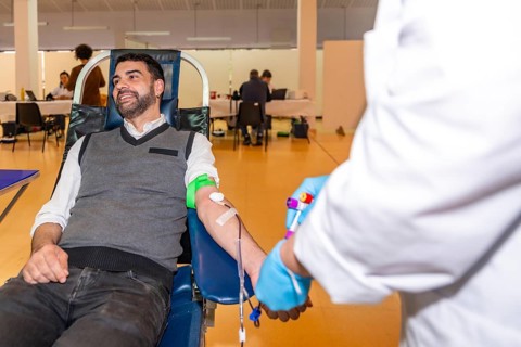 Man sitting on a comfortable chair while donating blood in a center next to a nurse in uniform