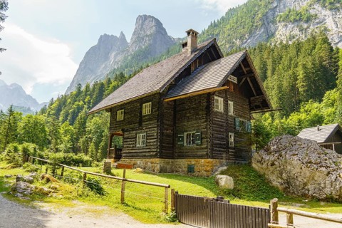 A traditional wooden house in the Alps, surrounded by a picturesque mountain landscape and lush,