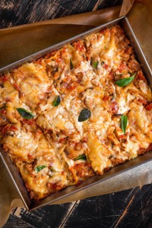 Close-up of a traditional italian lasagna made with minced beef bolognese sauce topped with basil