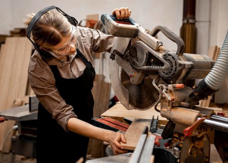 Female carpenter studio using electric saw
