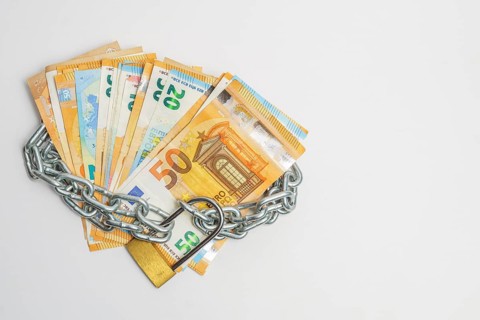 Pile of euro banknotes tied with a chain and a padlock isolated on a white background