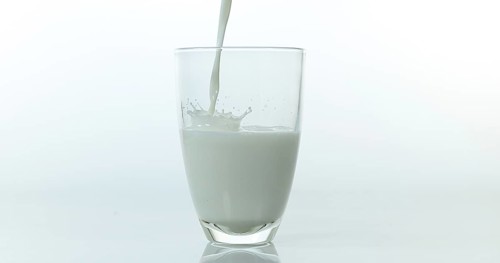 Milk being poured into Glass against White Background