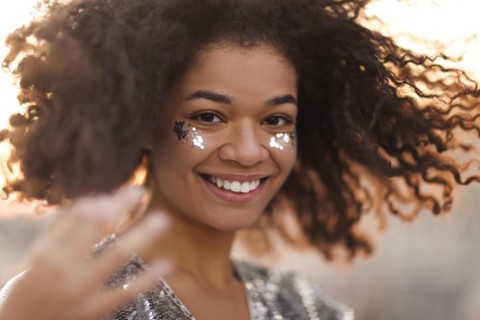 Close up portrait of overjoyed charming african american woman with curly hair and glitter on