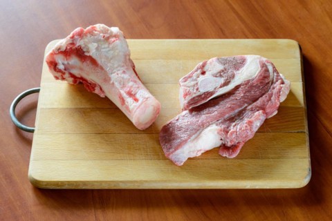 Meat of beef and marrowbone on a wooden cutting board, will be boil for the preparation of broth