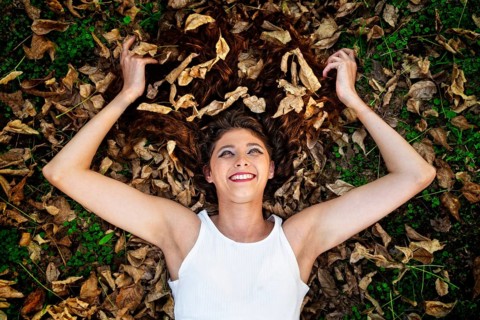 A happy young woman lies in the autumn leaves. Beautiful eyes, warm emotions