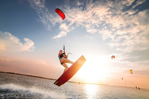 Sports shot of a young caucasian woman in a wetsuit doing a trick in the air against the backdrop