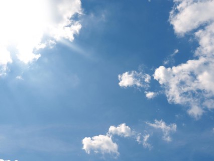 Bright hot sun on a blue summer sky with small clouds