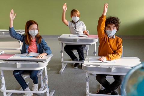 Front view children with medical masks school raising their hands