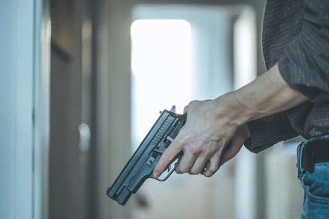 Undercover police agent is holding a black weapon in his hand, ready for shoot