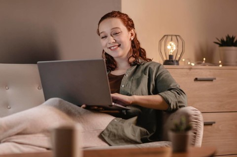 Smiley woman using laptop home couch