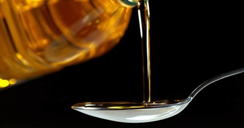 Olive Oil Pouring from Spoon on Black Background