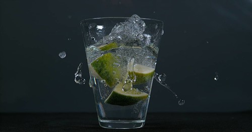 Green Citrus (citrus aurantifolia), falling into a Glass of Water
