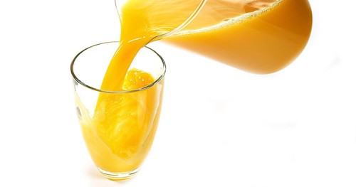 Orange Juice being poured into Glass against White Background