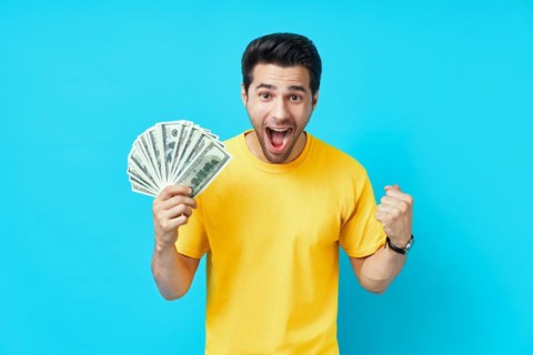 Happy excited man showing money banknotes on blue background. Business, win, income, success