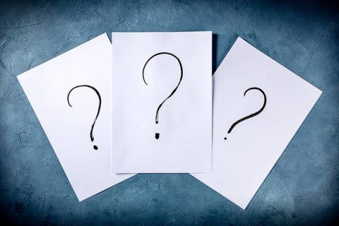 Question marks, written in ink on a piece of standard office paper, shot from the top