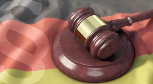 Richterhammer auf Deutschlandfahne und Paragrafenzeichen im Vordergrund. Judge's gavel on the flag