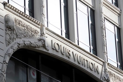 Logo of the French luxury fashion brand Louis Vuitton on the façade of a boutique in the shopping