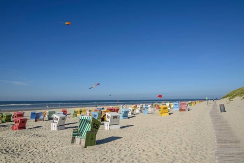Colourful beach chairs and kites on a sunny beach with blue sky and sea, langeoog, east frisia,
