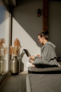 Woman in bathrobe sitting with a laptop on her lap in a garden