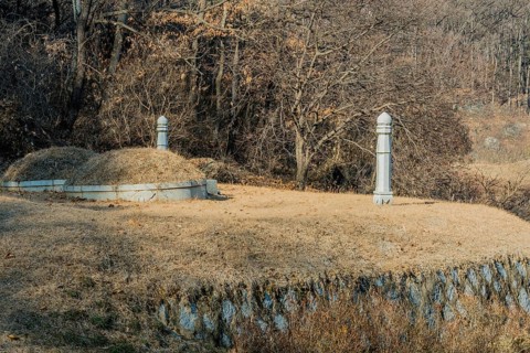Unmarked burial mounds on flat piece of land in wooded area on side of mountain on sunny winter