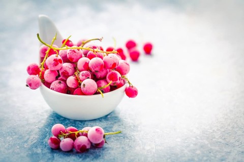 Frozen red currant in bowl on kitchen table