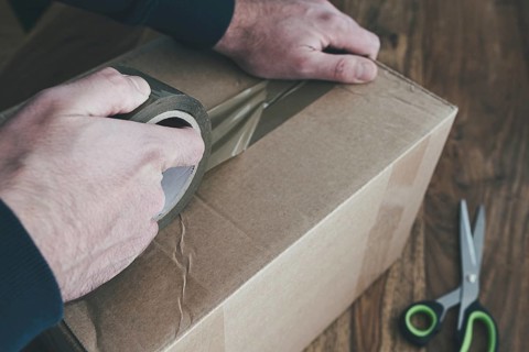 close-up of person sealing up shipping box with parcel tape, pruchase return and return of goods
