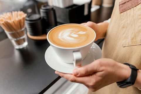 Side view female barista holding decorated cup coffee hands