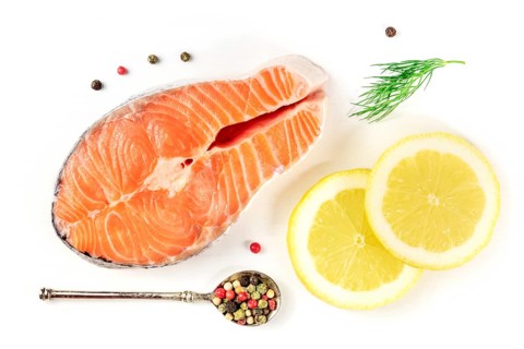 Salmon steak, shot from the top on a white background with lemon, dill, and pepper