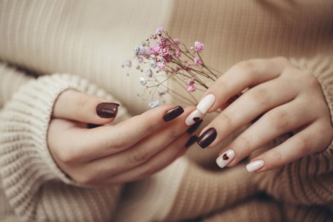 Close up view of beautiful female hand with fashion manicure nails holding hypsophila flowers,