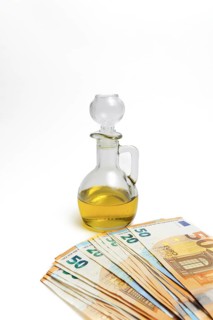 Euro banknotes in front of a bottle of olive oil isolated on a white background, oil price rise