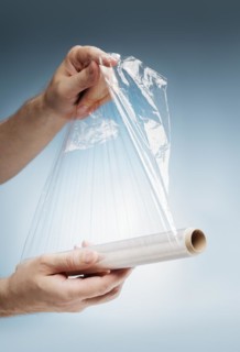 Man holding a roll of plastic film, typically used for sealing food items