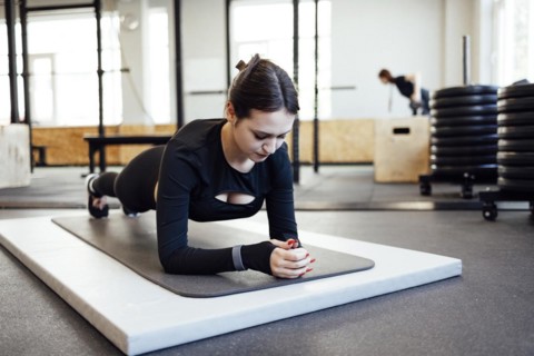 Young beautiful woman stretching and warming up before workout in fitness gym, Sport and healthcare