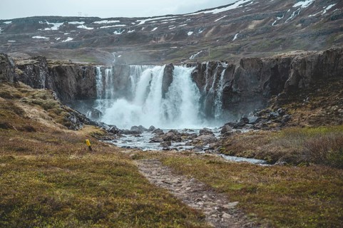 Beautiful Waterfall at Seydisfjordur, Iceland with snow mountains in the background